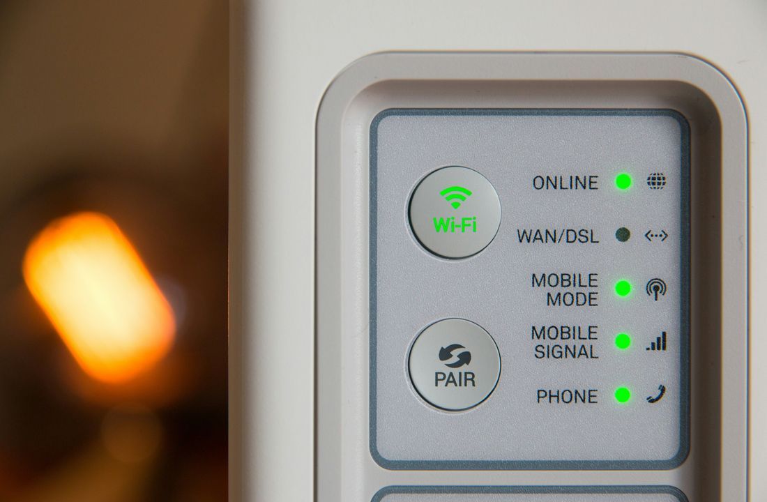 Home router front panel showing Wi-Fi and pair buttons and green online status lights