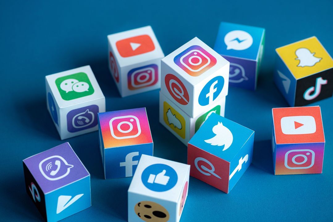 Paper cubes printed with social media logos including Facebook, Instagram, TikTok and Twitter