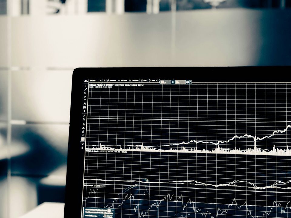 Laptop screen displaying a financial trading chart with grid lines and indicators