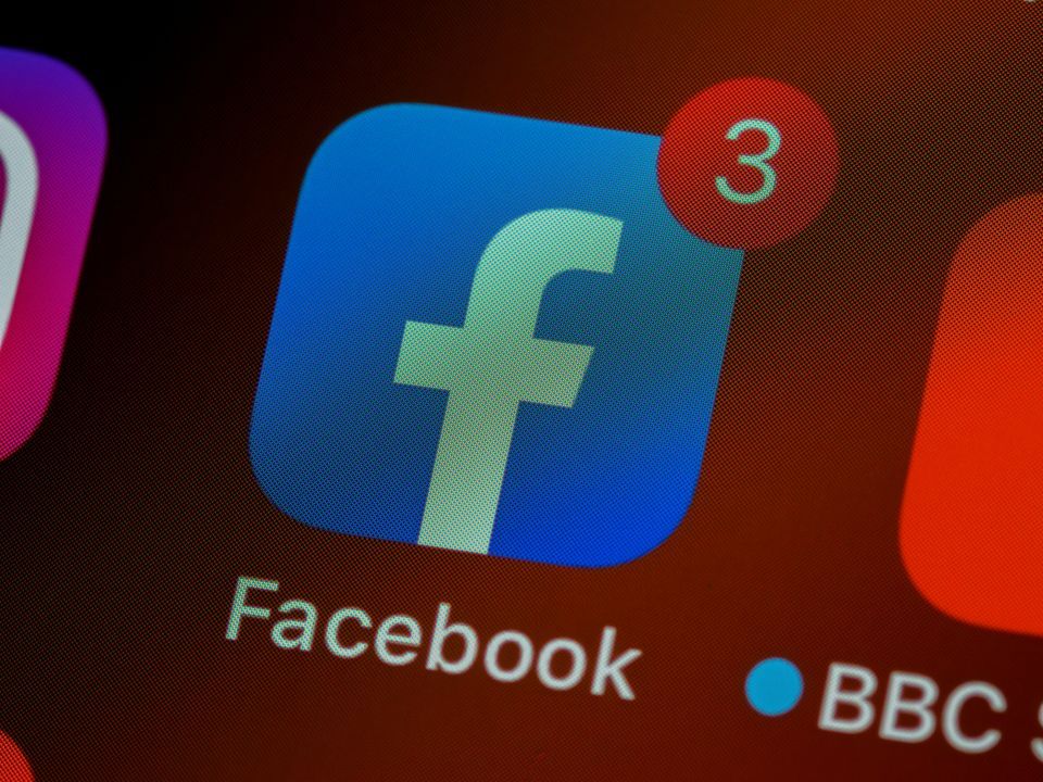 Close-up of the Facebook app icon on a phone screen with three notifications